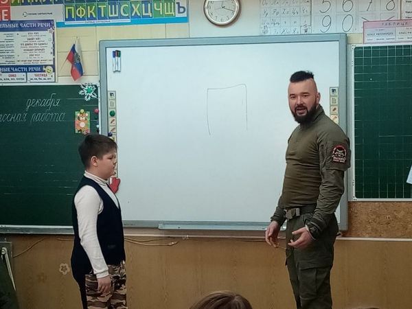 Мальчик у доски с инструктором на тренинге в школе